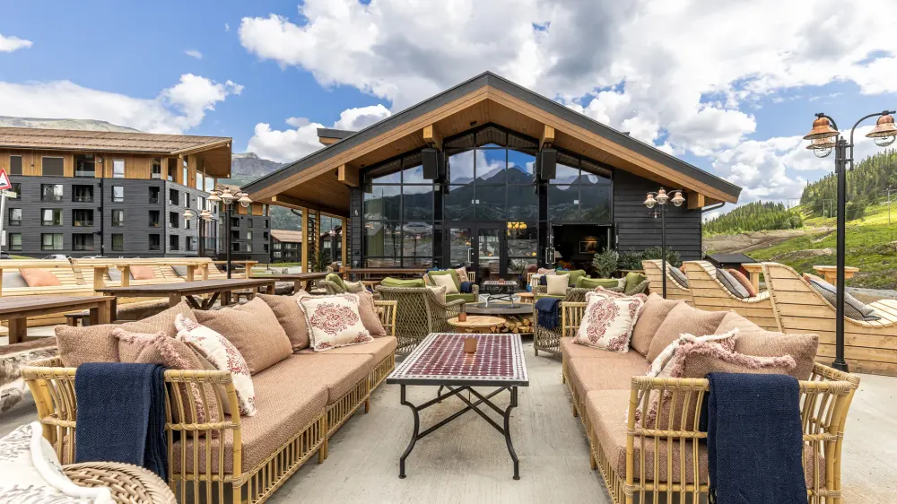 Solrik uteservering med lounge-sofaer og fjellutsikt ved Rambler på Fýri Resort