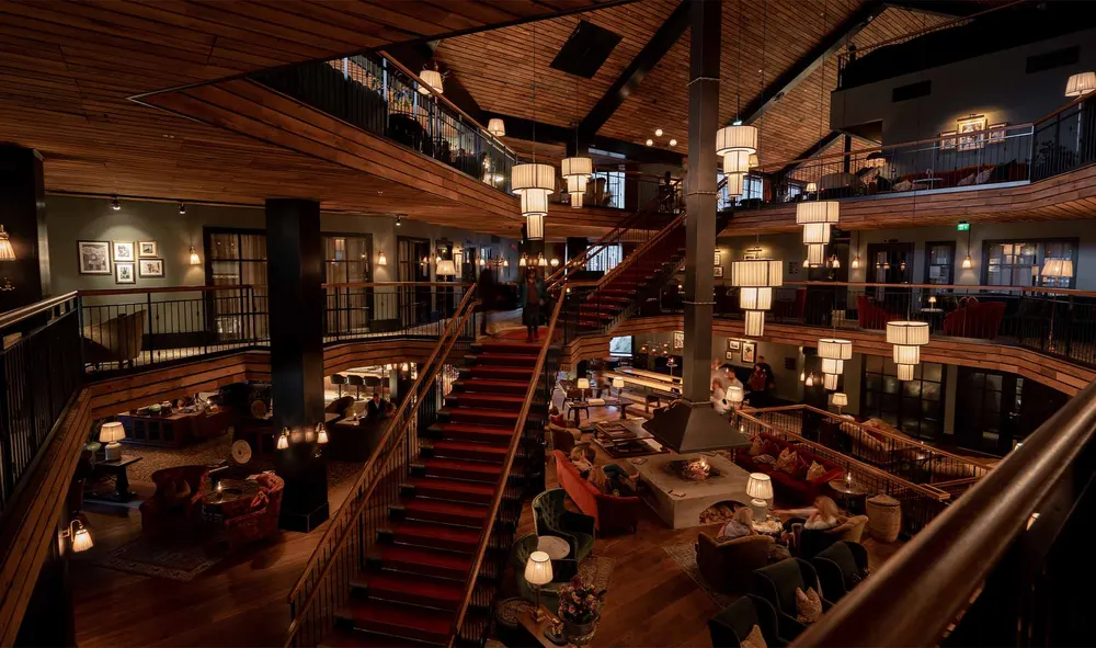 Den store lobbyen på Fýri Resort med trapper, lysekroner og peisstue