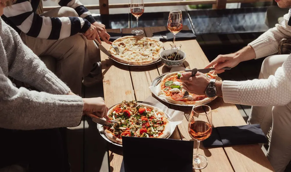 Nystekte pizzaer og rosévin på terrassebordet en solrik dag