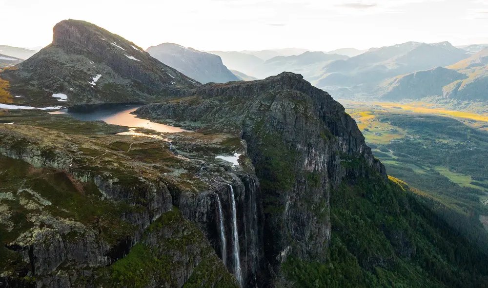 Luftfoto av fjell, foss og fjellvann over den grønne Hemsedal-dalen en sommerkveld