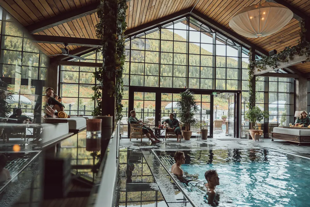 Pool Club med panoramavinduer mot fjellsiden og gjester i bassenget