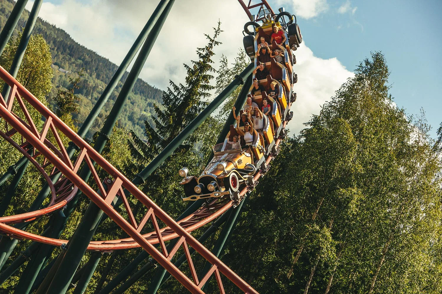 Il Tempo Extra Gigante på Hunderfossen — den gigantiske gullbilen fra Flåklypa full av folk med armene i været på vei nedover berg-og-dal-banen