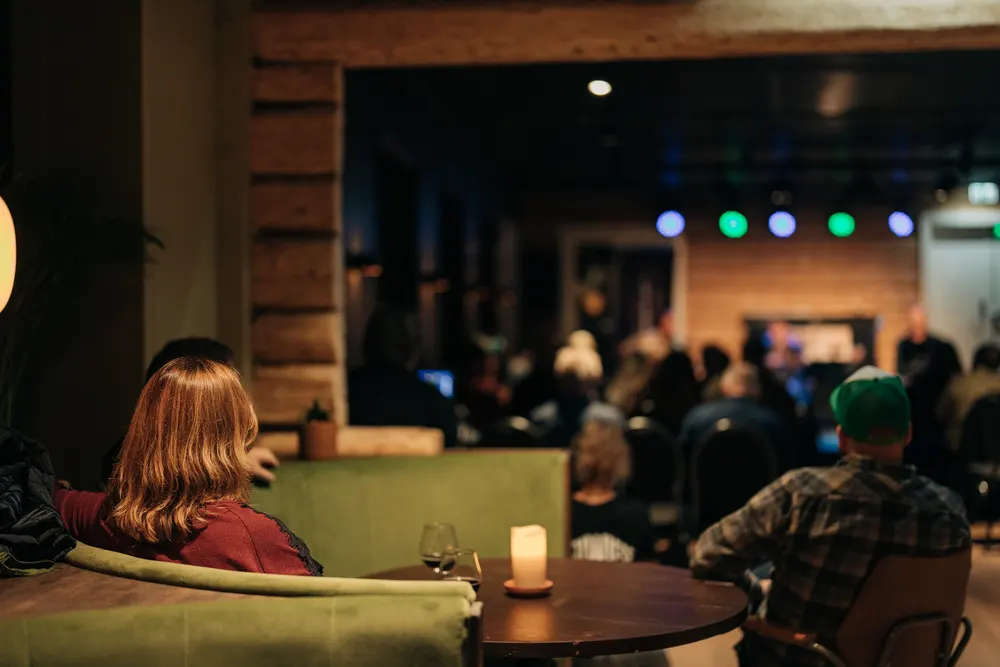 Stemning inne på Wiese kulturhus i Lillehammer — publikum foran scenen i varmt lys